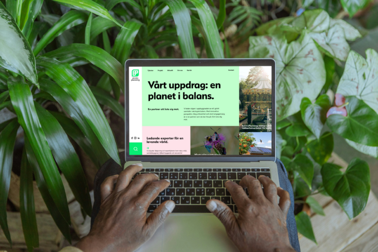 A person typing on a laptop with the Enviro Planning website displayed on the screen, surrounded by green plants