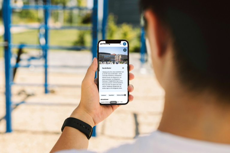 Close-up of a person's shoulder outdoors while using the mobile-optimized website goteborg.com on a smartphone.