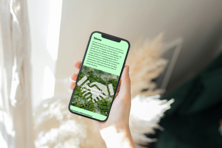 A hand holding a smartphone with Enviro Planning's service page displayed on the screen, featuring green and white sustainability services