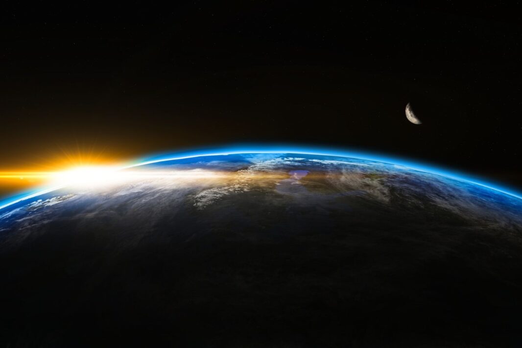 A view of planet Earth shows a colorful sunrise on the horizon, while a crescent moon appears against the darkness of space. The image illustrates how artificial intelligence (AI) and digital transformation are reshaping global industries. 