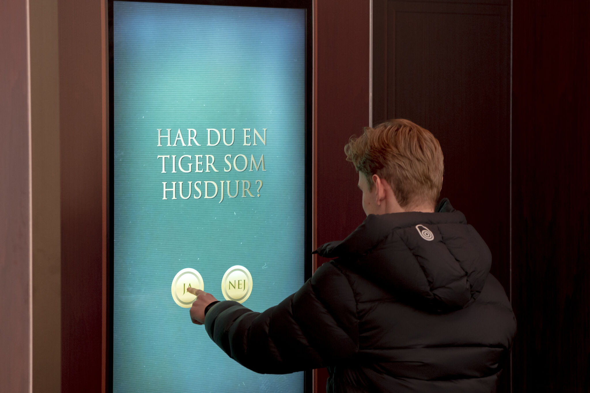 Närbild på interaktiv pekskärm i offentlig miljö med texten "HAR DU NÅGONSIN LJUGIT FÖR EN VÄN?" och två svarsknappar: JA eller NEJ. Skärmen är en del av en kampanj för TV4:s program Förrädarna.
