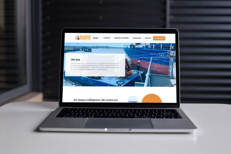 A laptop is open on a table, displaying Dawab's new website. The screen shows a bright, clean layout featuring an image of ships at a dock and a clear navigation menu for the company's services. 