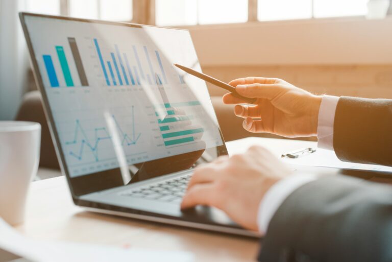 A person pointing at a bar chart in a report on a laptop